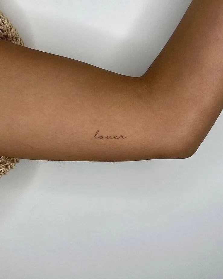 “lover” tattoo on the upper arm